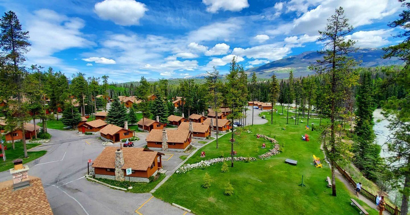 Luchtfoto van Becker's Chalets Jasper  met hutten met oranje daken, groene gazons en bomen onder een blauwe hemel.