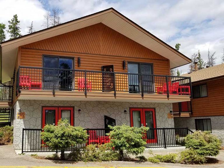Appartementengebouw van Becker's Chalets te Jasper met twee verdiepingen, beige gevelbekleding, balkons met rode accenten en struiken aan de voorzijde.