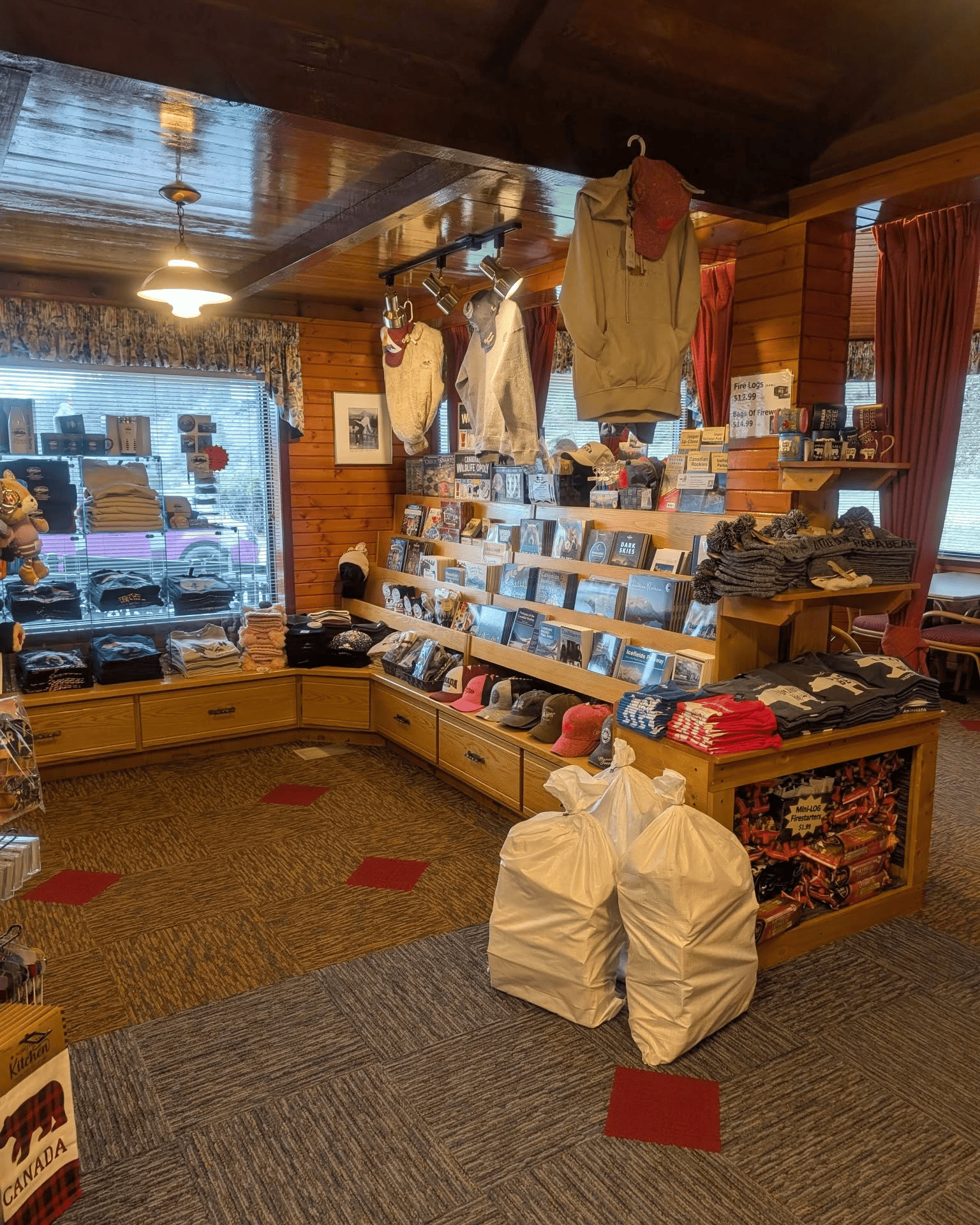 Gezellig winkelinterieur van Becker's Chalets Jasper met boekenplanken, hangende overhemden en een houten plafond.