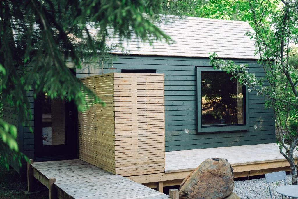 Kleine, moderne sauna van Black Forrest Cabins, Mahone Bay met grijze en houten gevelbekleding, te midden van bomen en rotsen.