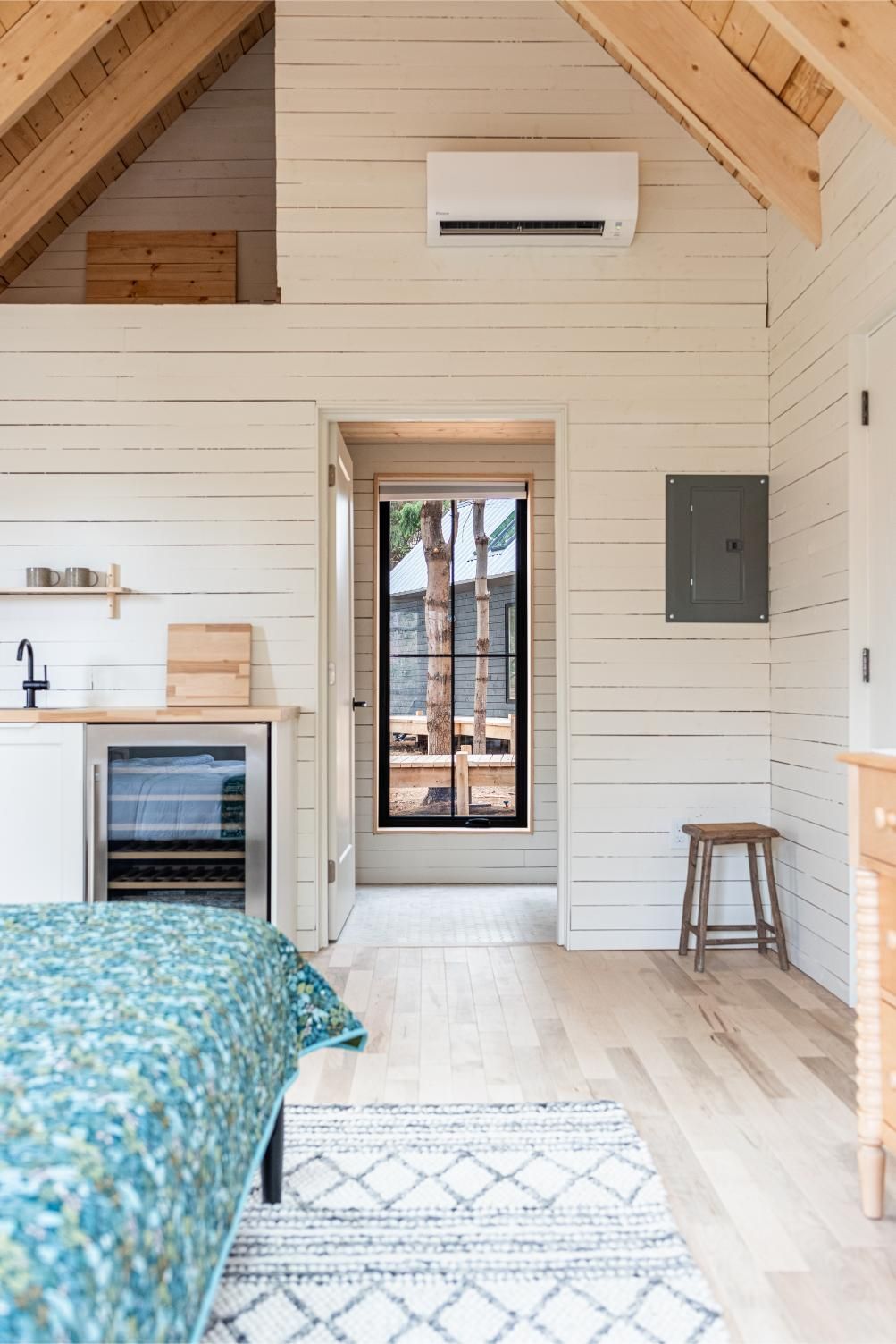 Gezellige zolderkamer van Black Forrest Cabins, Mahone Bay met houten lambrisering, dakraam, bed, raamdeur en airconditioning aan de muur.