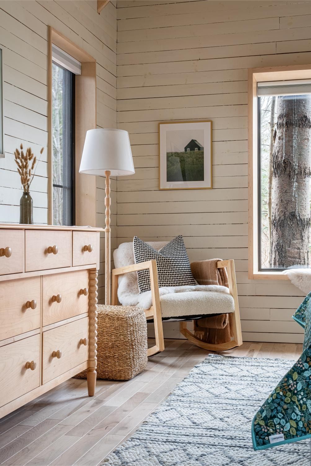 Gezellige beige woonkamer van Black Forrest Cabins, Mahone Bay met geweven stoel, staande lamp, dressoir en ingelijste kunst aan de muur bij een raam.