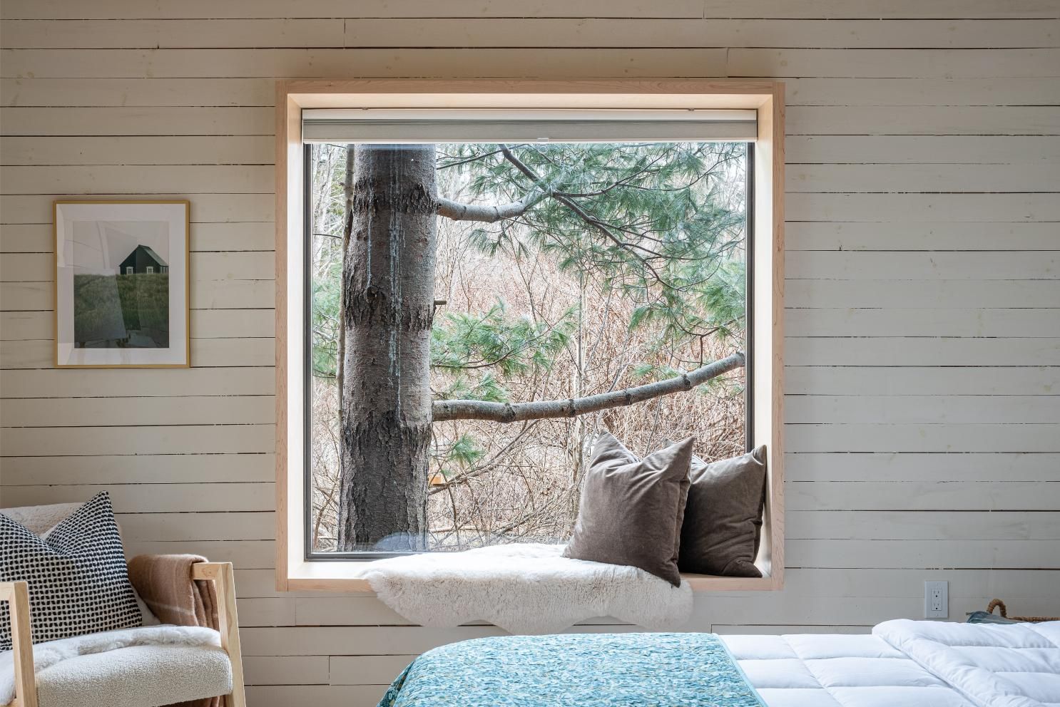 Gezellige slaapkamer van Black Forrest Cabins, Mahone Bay met witte houten lambrisering, een grote vensterbank en uitzicht op dennenbomen buiten.