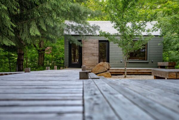 Een houten terras leidt naar de sauna van Black Forrest Cabins, Mahone Bay, omgeven door groene bomen en bos.