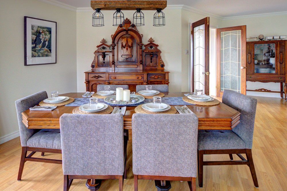 Elegante eetkamer met een houten tafel, gestoffeerde stoelen en een sierlijke antieke kast tegen de achterwand.