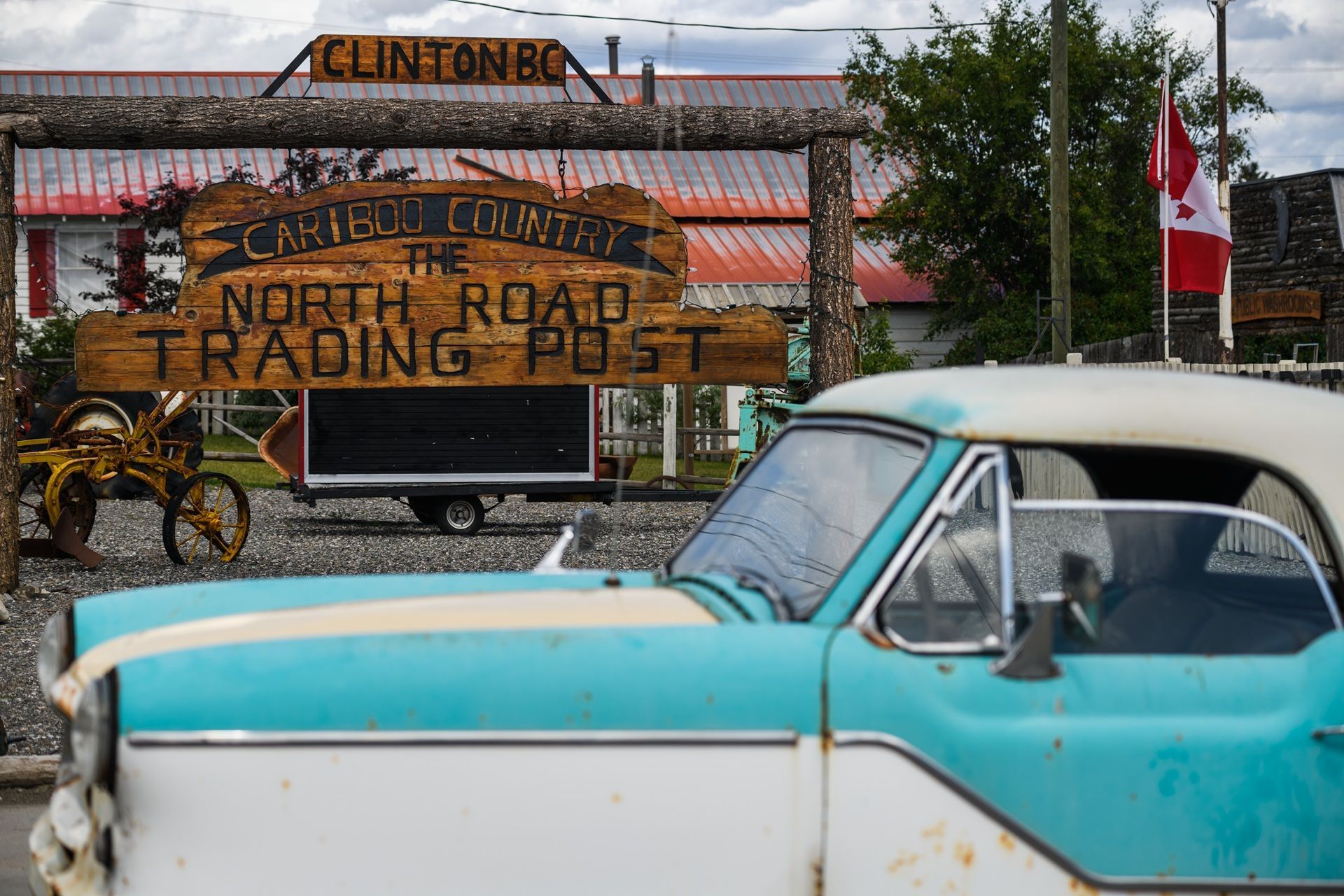 Een vintage turquoise auto staat geparkeerd voor een bord met 