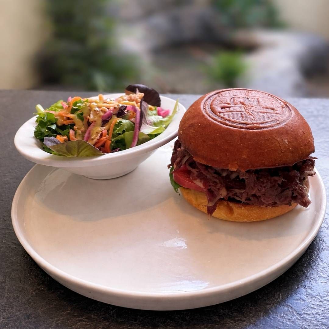 Hamburger en kleurrijke salade op een wit bord, buiten geserveerd.