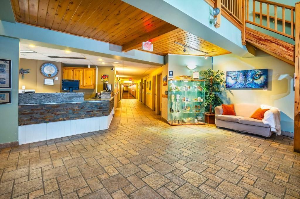 Lichte hotellobby met tegelvloer, houten plafond, receptiebalie, hal en zithoek.