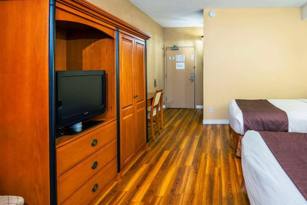 Hotelkamer van Cedar Meadow met twee bedden, houten meubels, tv en een gang bij de deur.