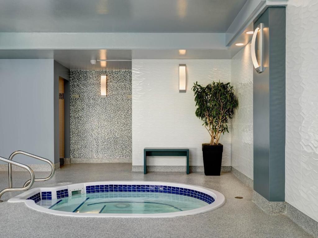 Binnenspa met betegelde jacuzzi, douchenis, bankje en potplant in een moderne ruimte