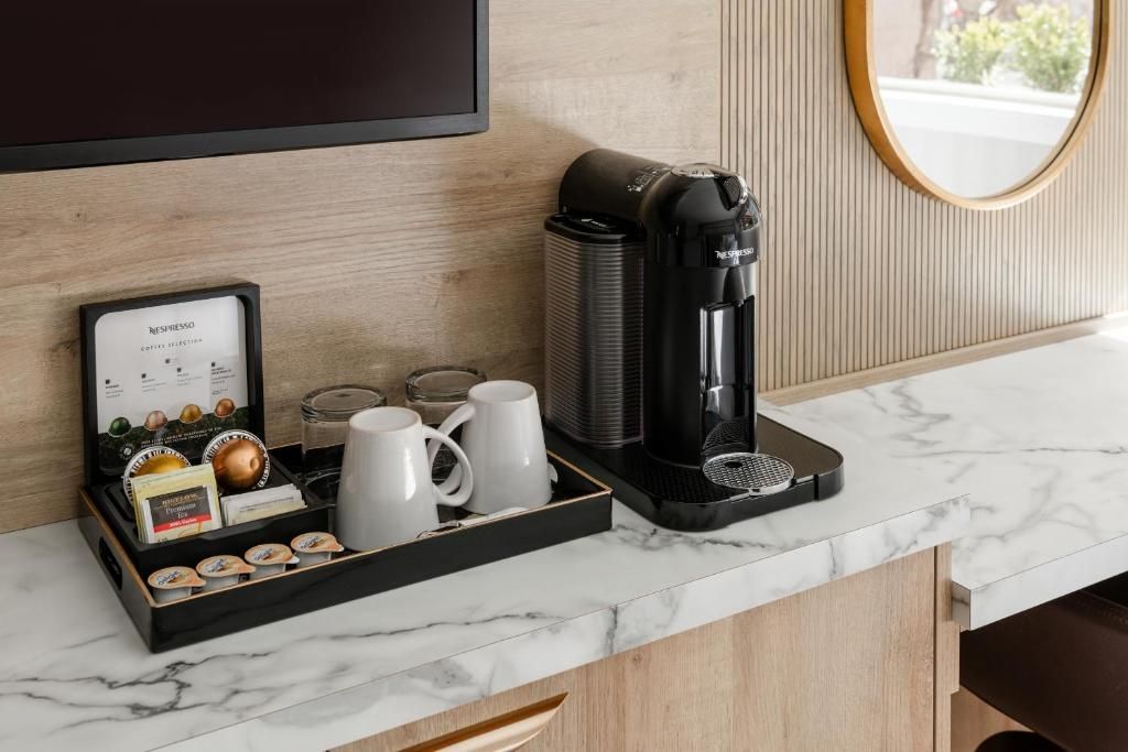 Koffiehoek op een marmeren aanrechtblad met een koffiezetapparaat, mokken en een dienblad met thee en snacks.