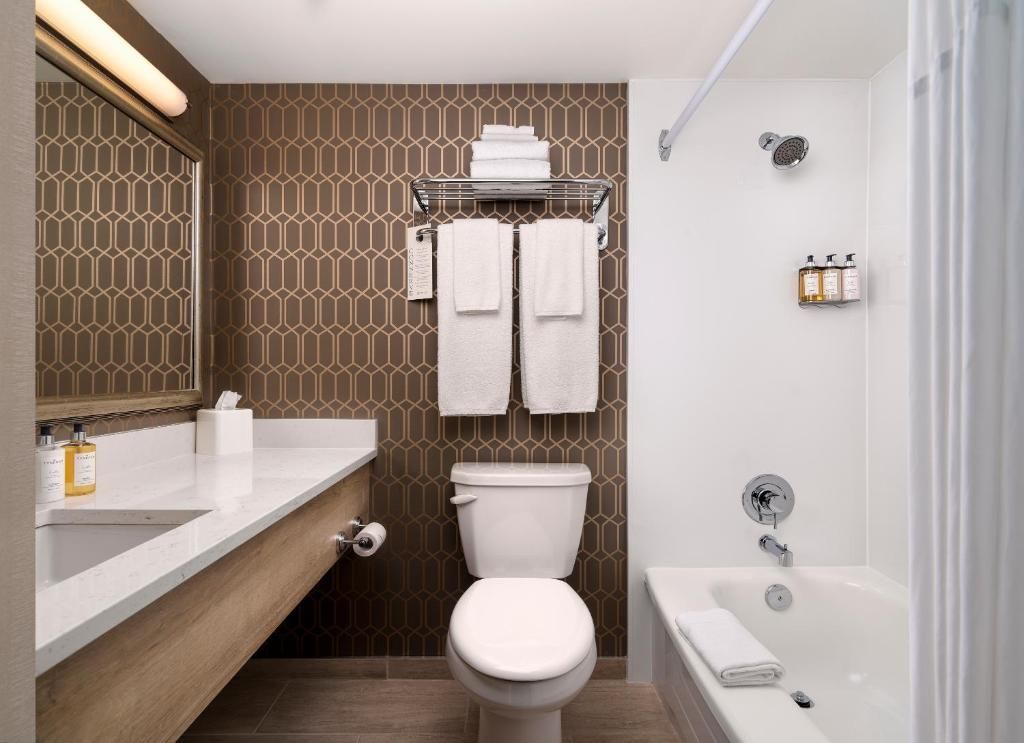Kleine badkamer met toilet, wastafel en badkuip in bruin-witte kleuren.