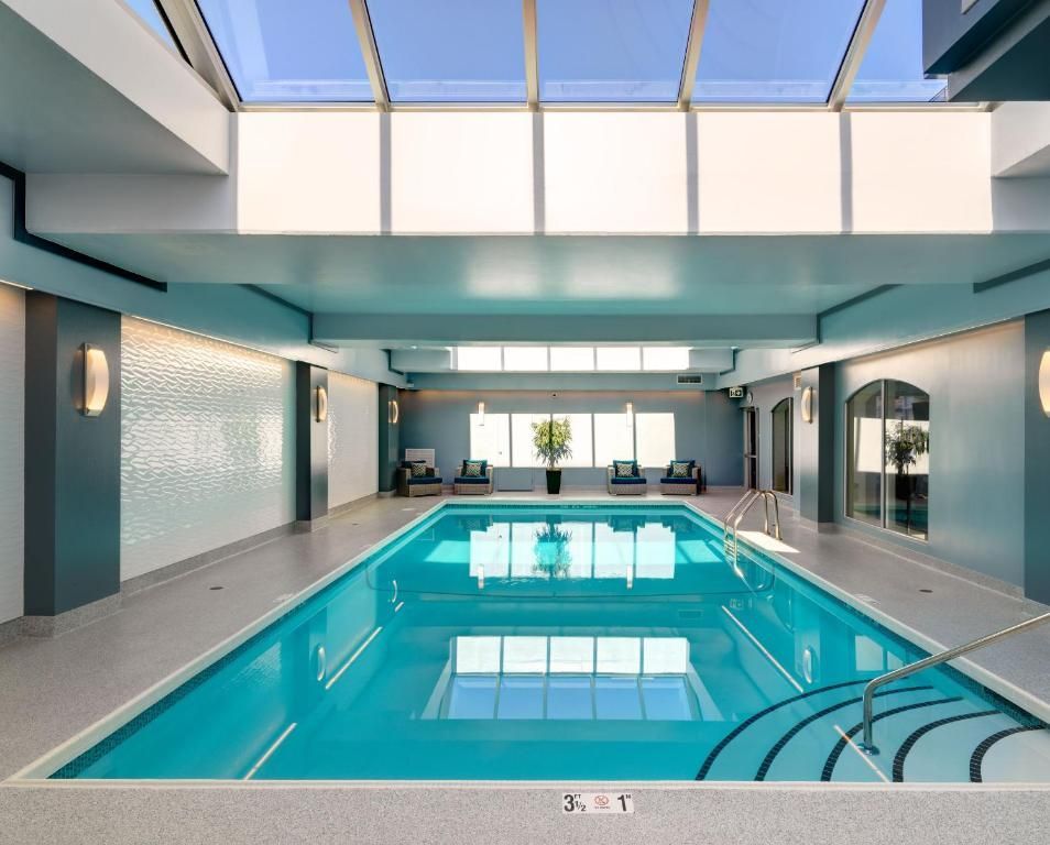 Binnenzwembad met turquoise water, dakramen en loungezitjes