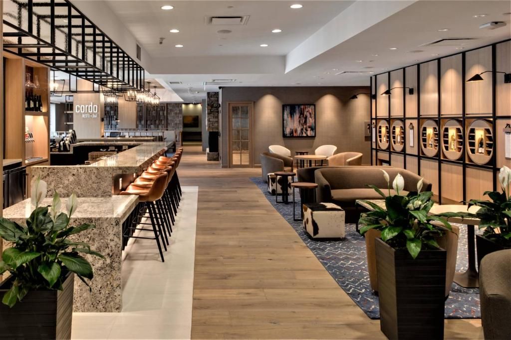 Moderne hotellobby met houten vloer, comfortabele zitgelegenheid, een bar en potplanten.