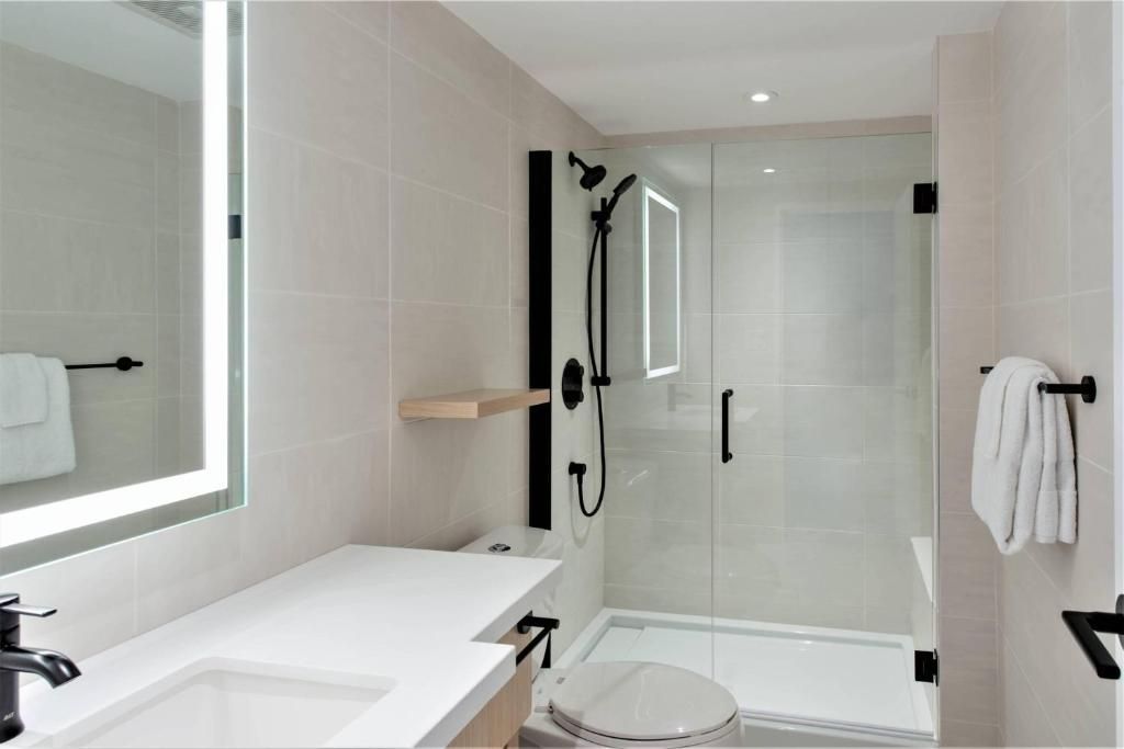 Moderne witte badkamer met inloopdouche, wastafelmeubel, spiegel en zwarte kranen.