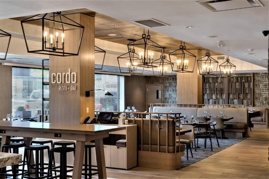 Modern restaurantinterieur met houten zitjes, hangende lantaarnlampen en een open zitgedeelte.