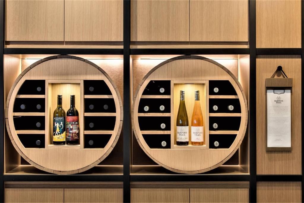 Houten wanddisplay met twee ronde nissen voor wijnflessen en een ingelijst menu aan de rechterkant.