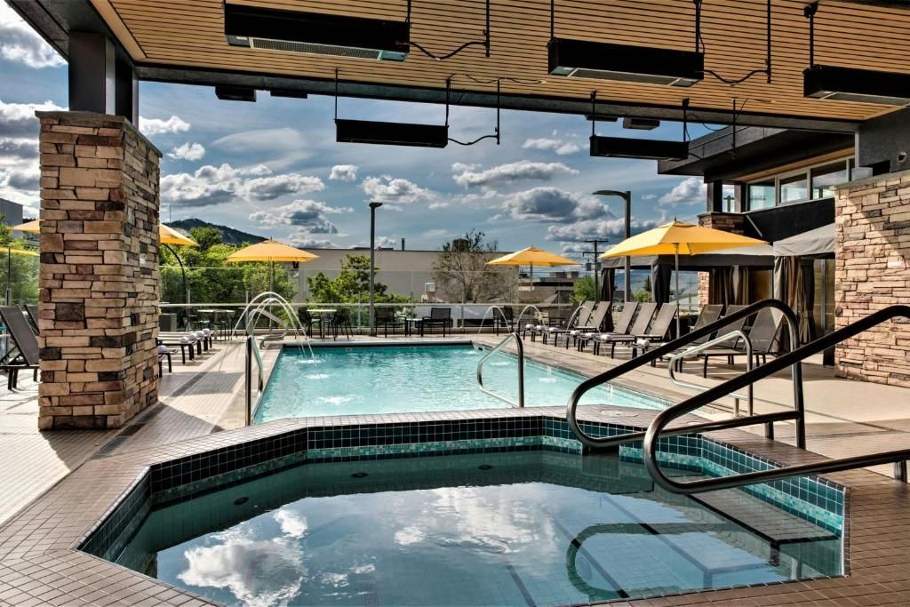 Overdekt zwembad van het resort met jacuzzi, ligstoelen en gele parasols onder een bewolkte hemel.