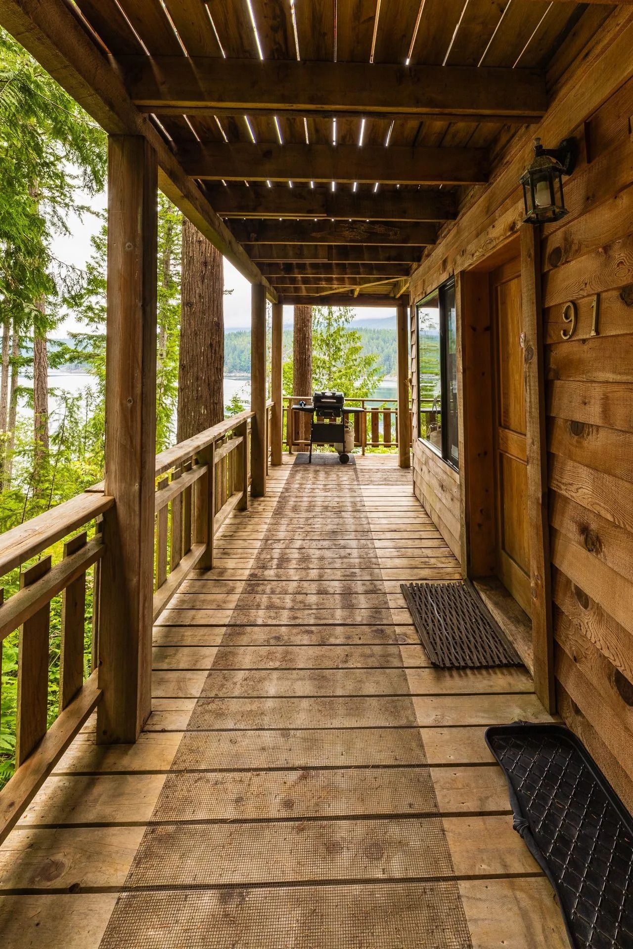 Houten veranda met balustrade, overdekt dak en uitzicht op het bos vanaf het terras.