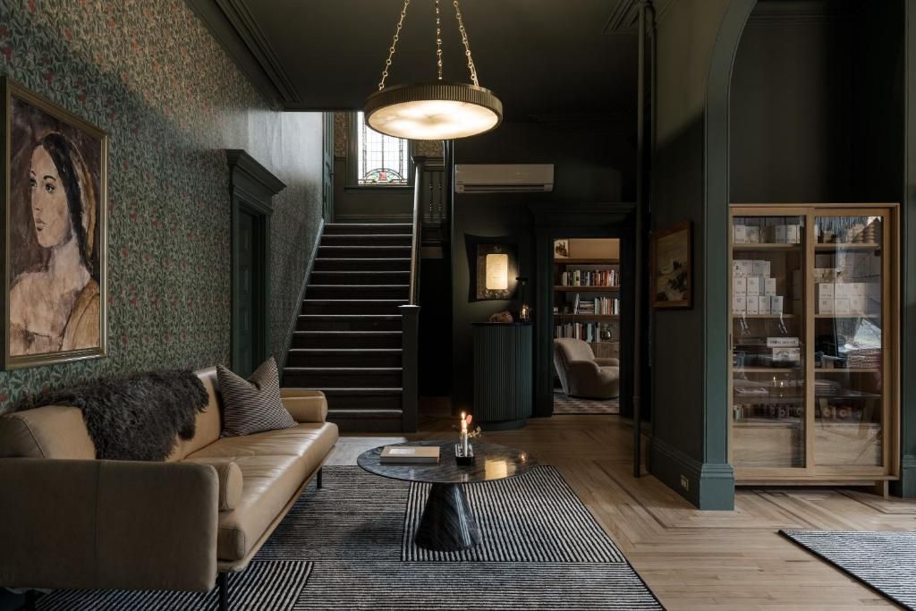 Gezellige, moderne woonkamer met bank, vloerkleed, hanglamp, trap en vitrinekasten.