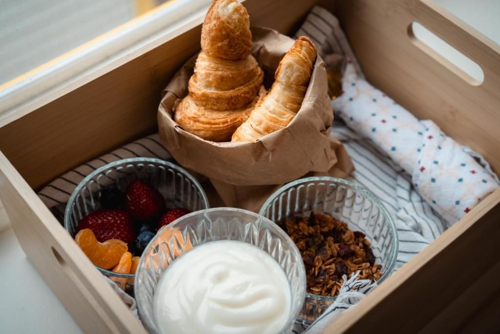 Houten krat met gebak, bessen, yoghurt, granola en een opgevouwen stoffen servet erin.