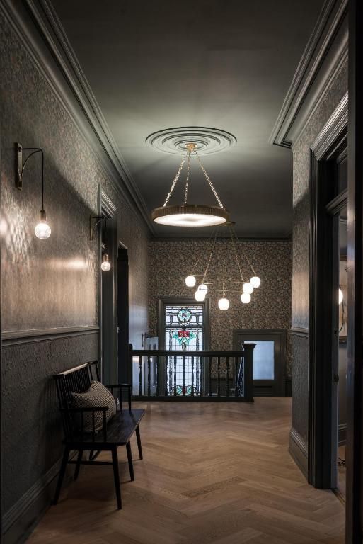 Elegante hal met houten vloer, donkere muren, hanglampen en een bankje bij de balustrade.