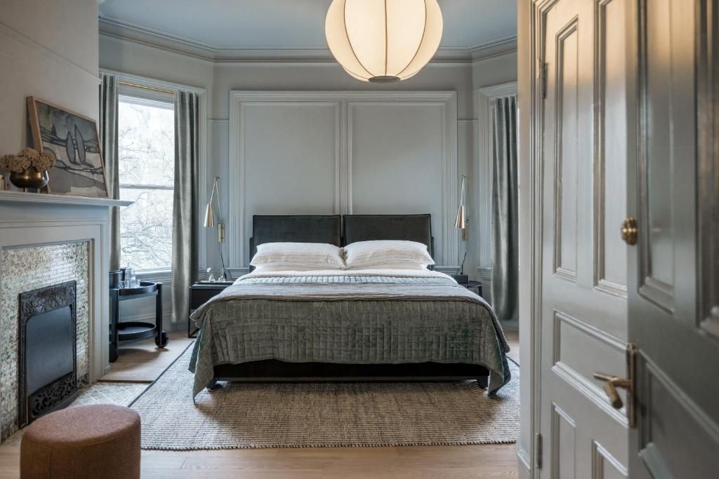 Elegante slaapkamer met een grijs bed, inbouwkasten, open haard en zacht natuurlijk licht.
