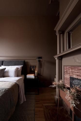 Gezellige slaapkamer met een bed, donkere muren en een open haard naast een vensterbank.