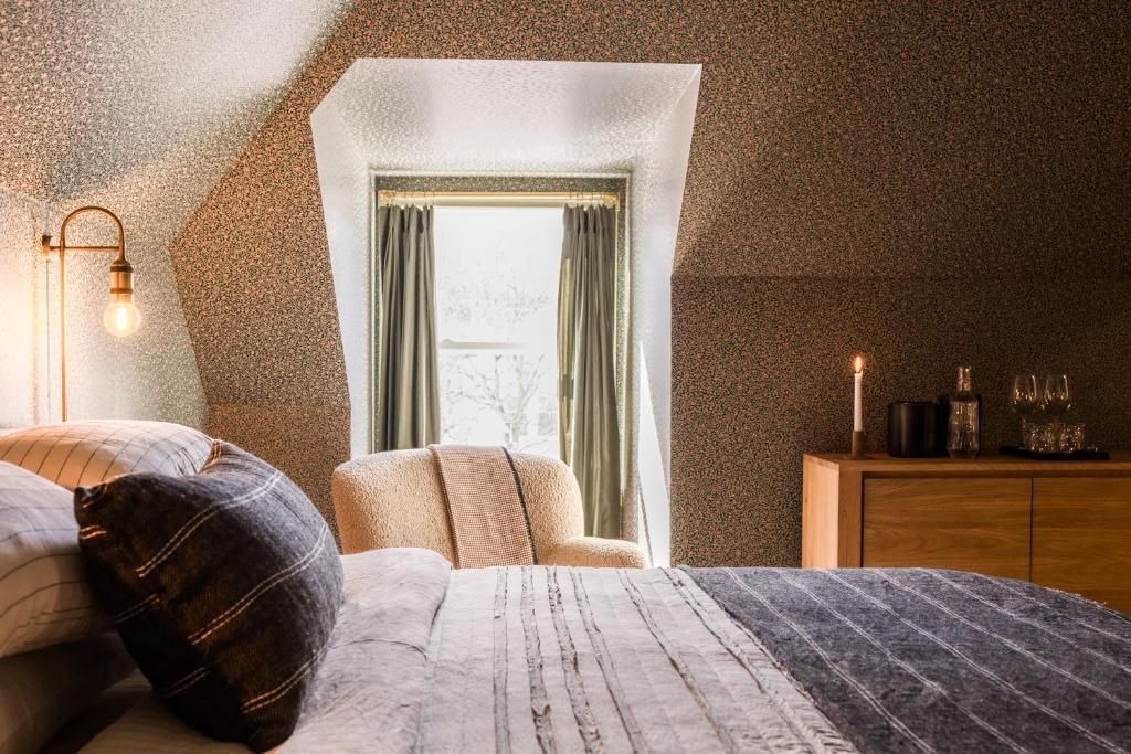 Gezellige slaapkamer met een bed, een vensterbank, warm lamplicht en muren met een structuur.