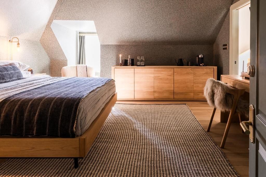 Gezellige zolderkamer met bed, commode, bureau en warme houten vloer en decoratie.