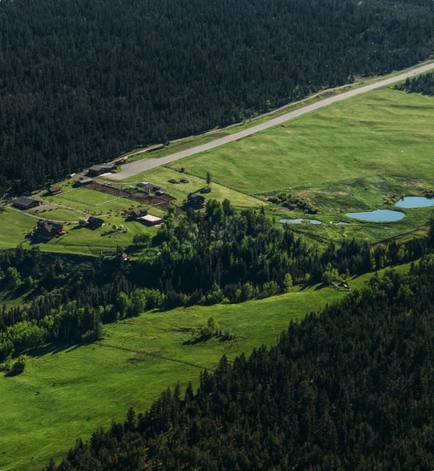 Luchtfoto van Echo Valley Ranch met groene velden en een weg langs dicht bos en vijvers.