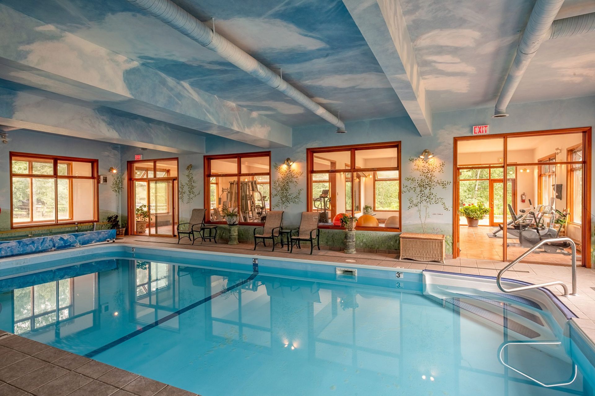 Overdekt hotelzwembad van Echo Valley Ranch met blauw water, ligstoelen en grote ramen.