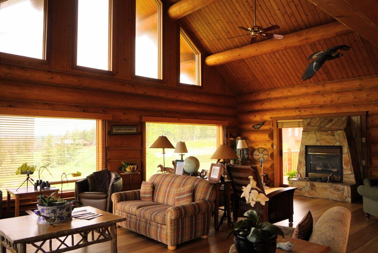Gezellige woonkamer van Echo Valley Ranch met gewelfd houten plafond, grote ramen, bank, tafel en stenen open haard.