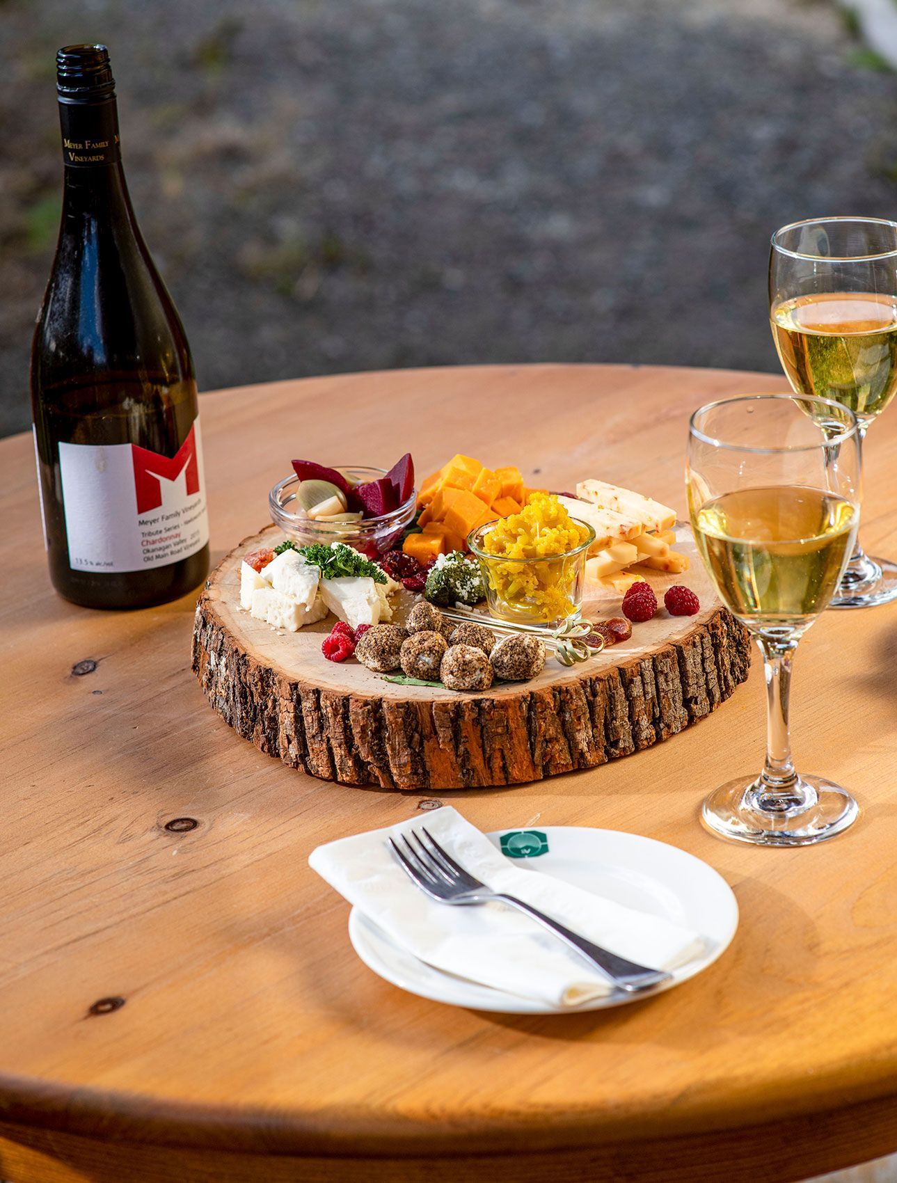Wijn en charcuterie uitgestald op een houten tafel bij Echo Valley Ranch, met een fles, glazen en een vork op een servet.