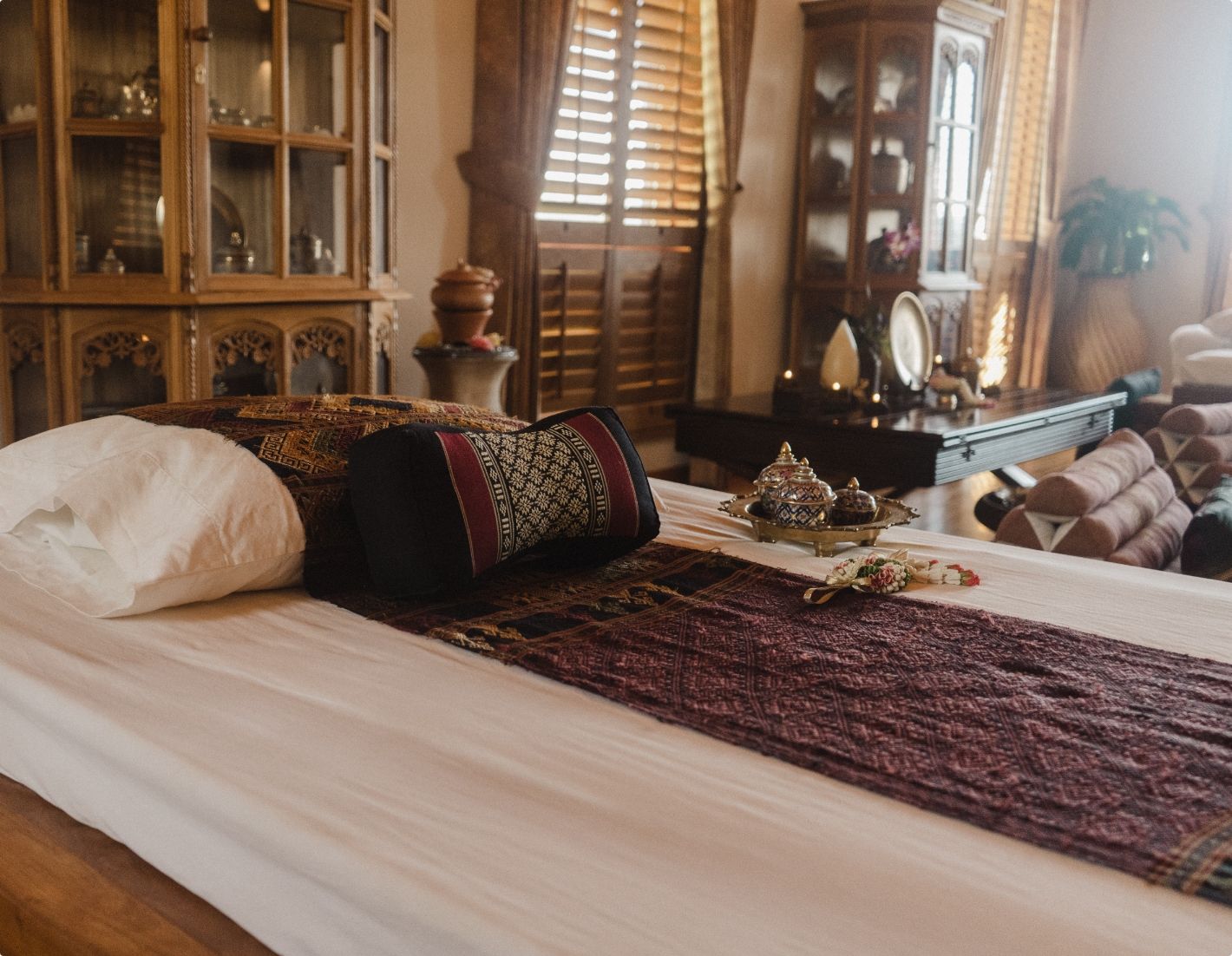De massage salon van Echo Valley Ranch met een groot bed, een vloerkleed met patroon, houten meubels en warm zonlicht dat door de luiken schijnt.
