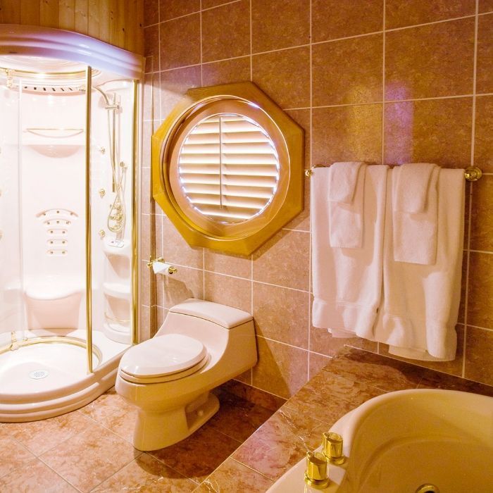 Luxe badkamer van Echo Valley Ranch met douche, toilet, rond raam, handdoeken en een wastafelblad van marmer.