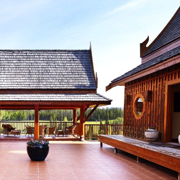 Traditioneel houten paviljoen met pannendak en betegelde binnenplaats van Echo Valley Ranch, met uitzicht op een potplant en een open landschap.