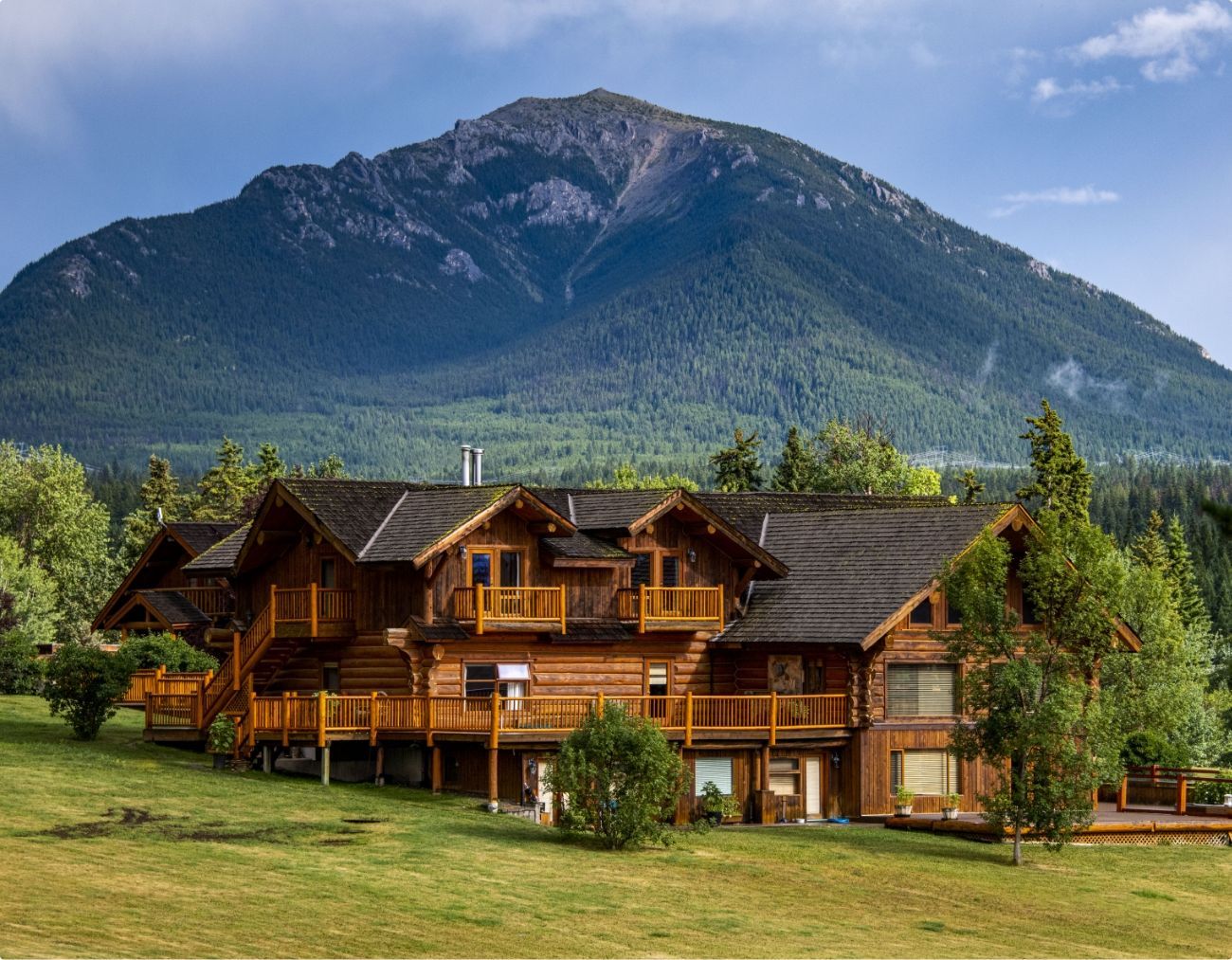 De Echo Valley Ranch in Canada met groen gazon en beboste bergtop op de achtergrond.