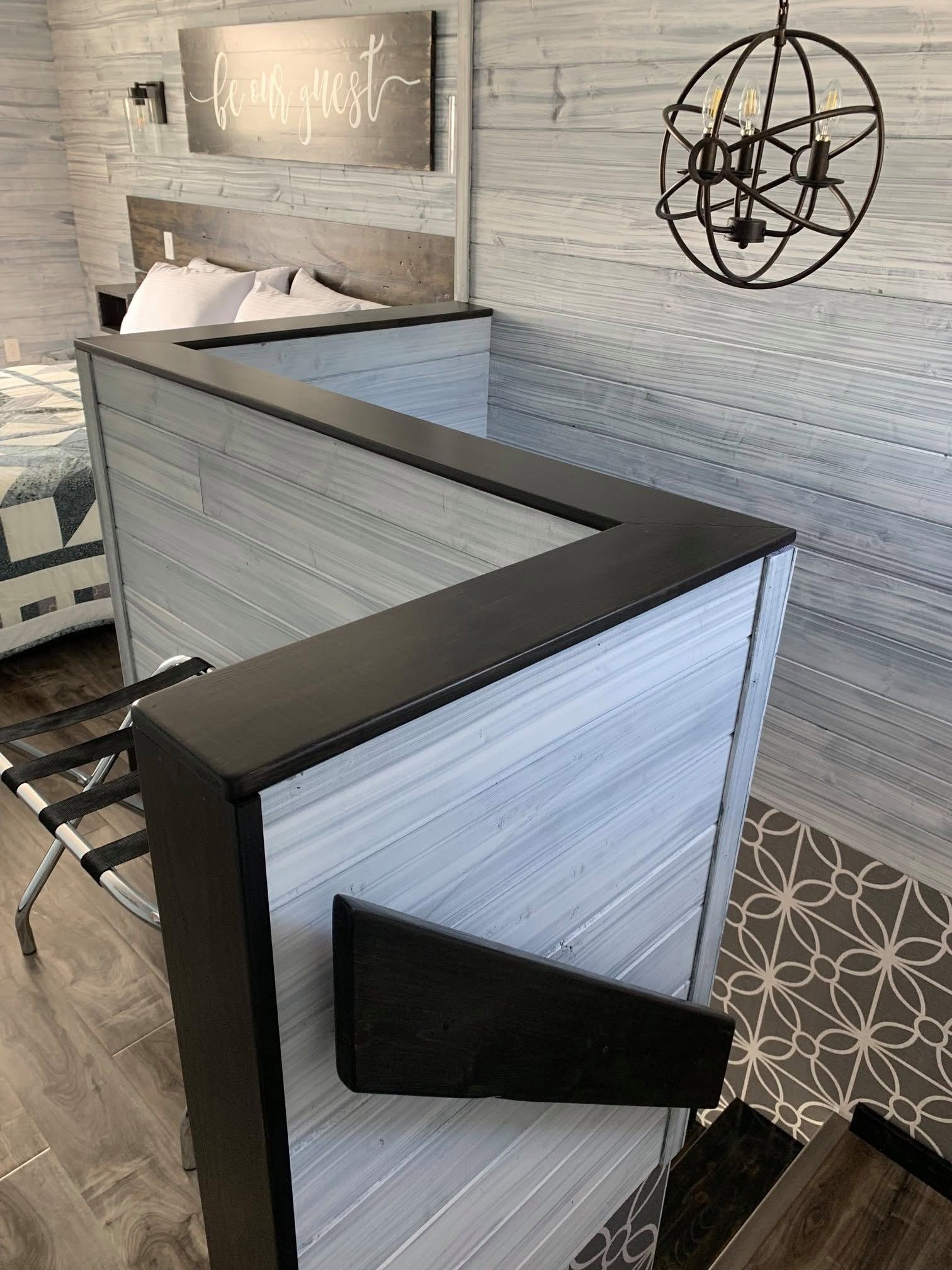Moderne receptiebalie met grijze houten lambrisering in een stijlvolle lobby, naast een wandbord en zwarte metalen decoratie.