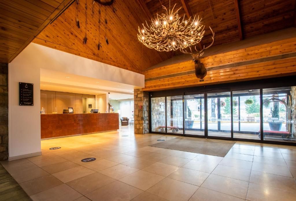 De lobby van Forest Park Hotel, Jasper met een gewelfd plafond van houten lambrisering, een kroonluchter, een tegelvloer en grote glazen deuren.