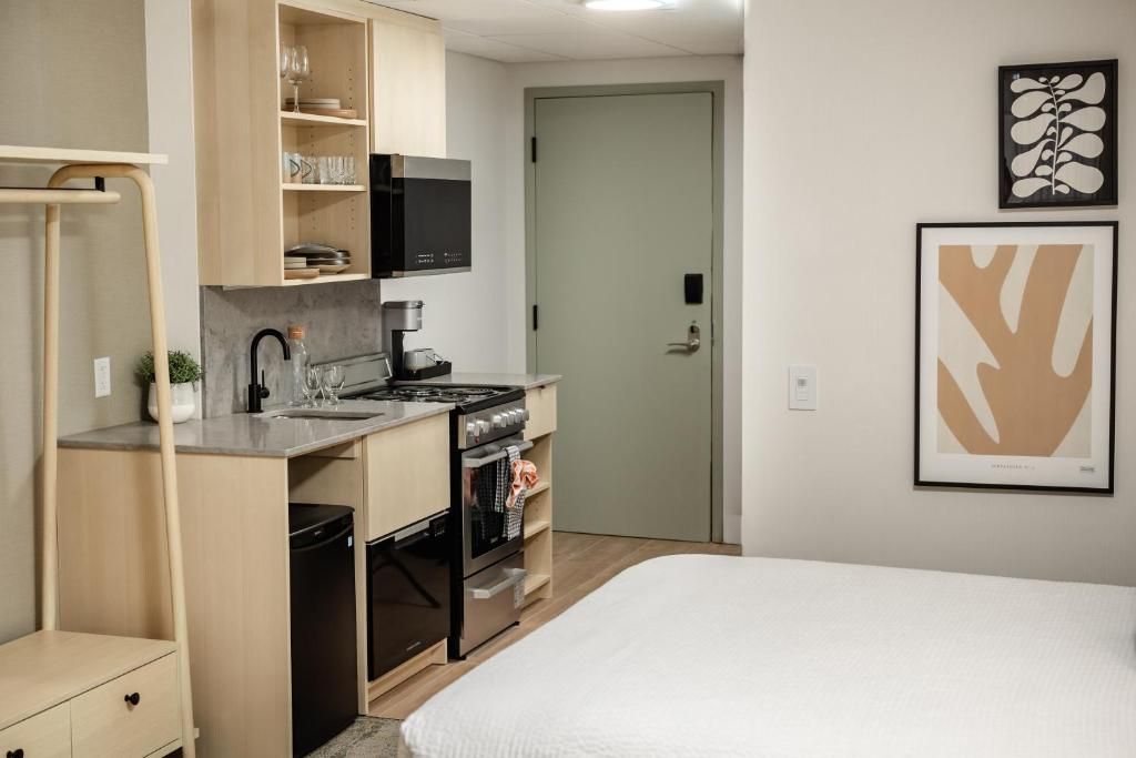 Klein studioappartement bij Forest Park Hotel, Jasper met een bed, kitchenette en ingelijste kunst aan de muur in neutrale tinten.