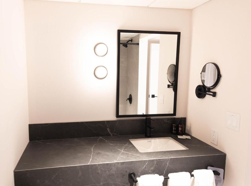 Moderne badkamermeubel met zwart marmeren blad, spiegel, wandlampen en opgevouwen handdoeken bij Forest Park Hotel, Jasper