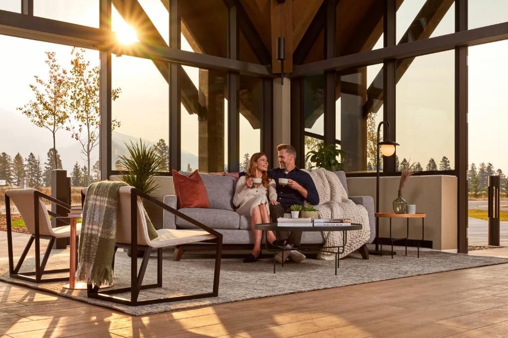 Mensen ontspannen op een overdekt terras met ligstoelen en het warme licht van de zonsondergang bij Forest Park Hotel, Jasper