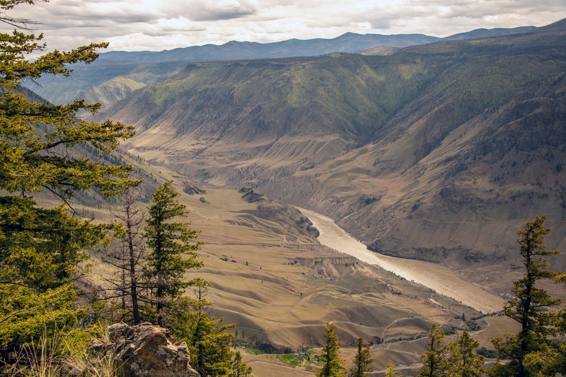 De Fraser Canyon in Edge Hills Park met een kronkelende rivier, steile hellingen en bomen onder een bewolkte hemel.