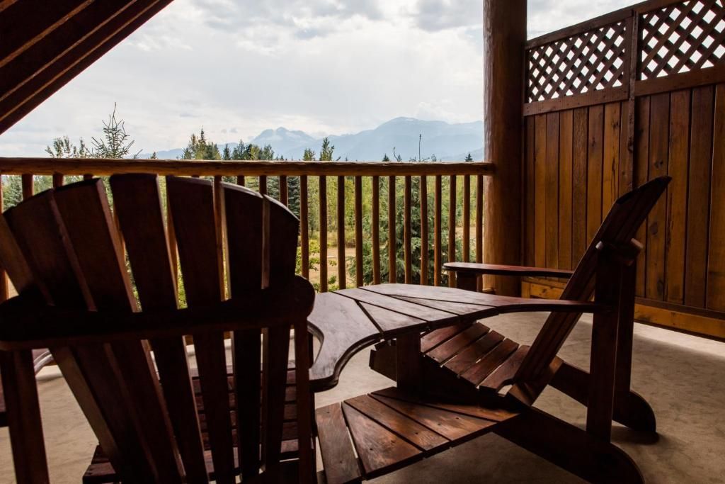 Houten verandastoelen met uitzicht op een mistig berglandschap door een overdekte veranda.
