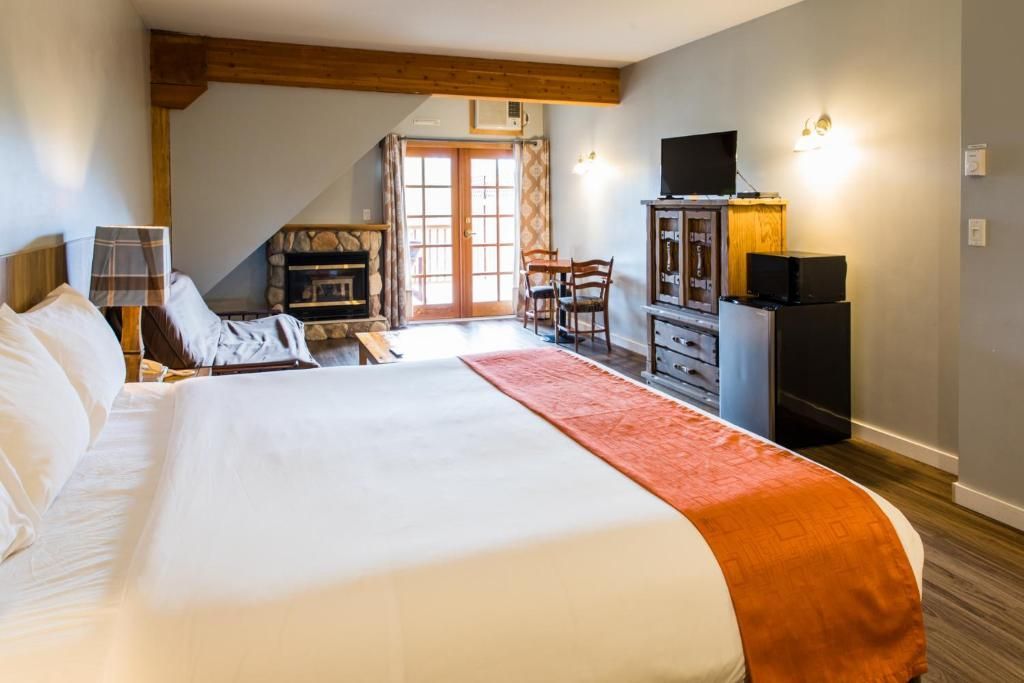 Grote slaapkamer met een bed, oranje loper, houten meubels en glazen schuifdeuren naar een balkon.
