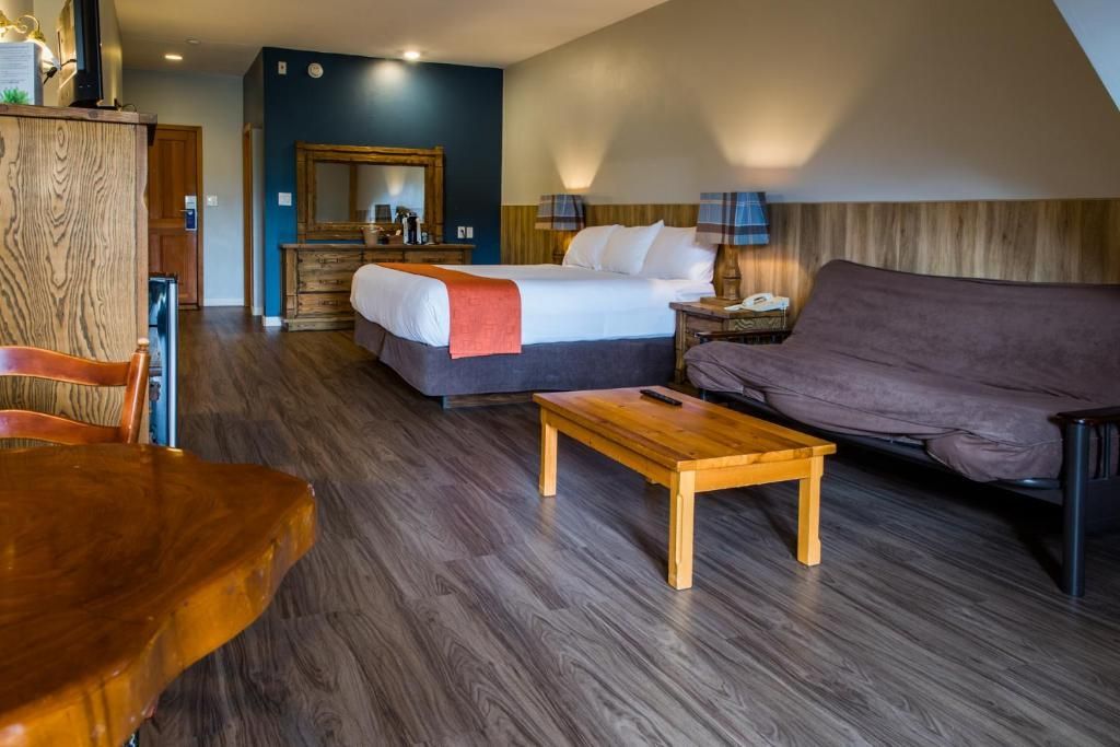 Hotelkamer met twee bedden, een bank, een salontafel en een bureau in een ruim, modern interieur.