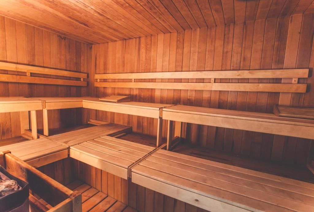 Sauna met houten lambrisering, houten banken en warme oranje verlichting.