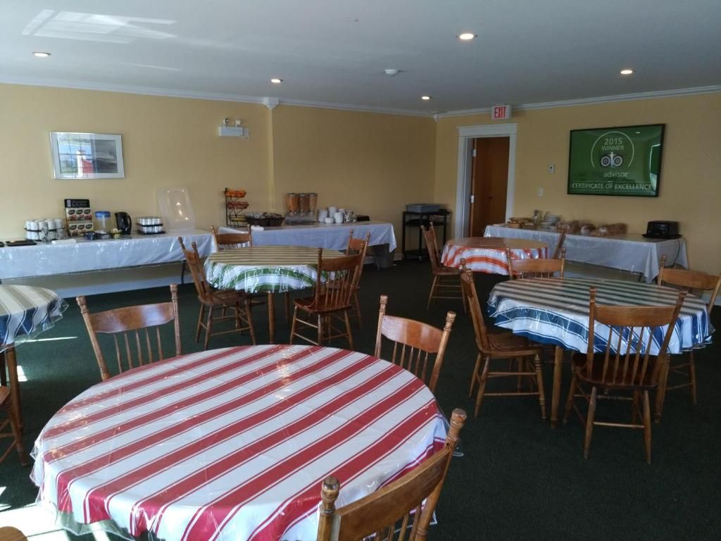 Een lege feestzaal met ronde tafels bedekt met rood-wit gestreepte tafelkleden en stoelen die in de zaal zijn opgesteld.