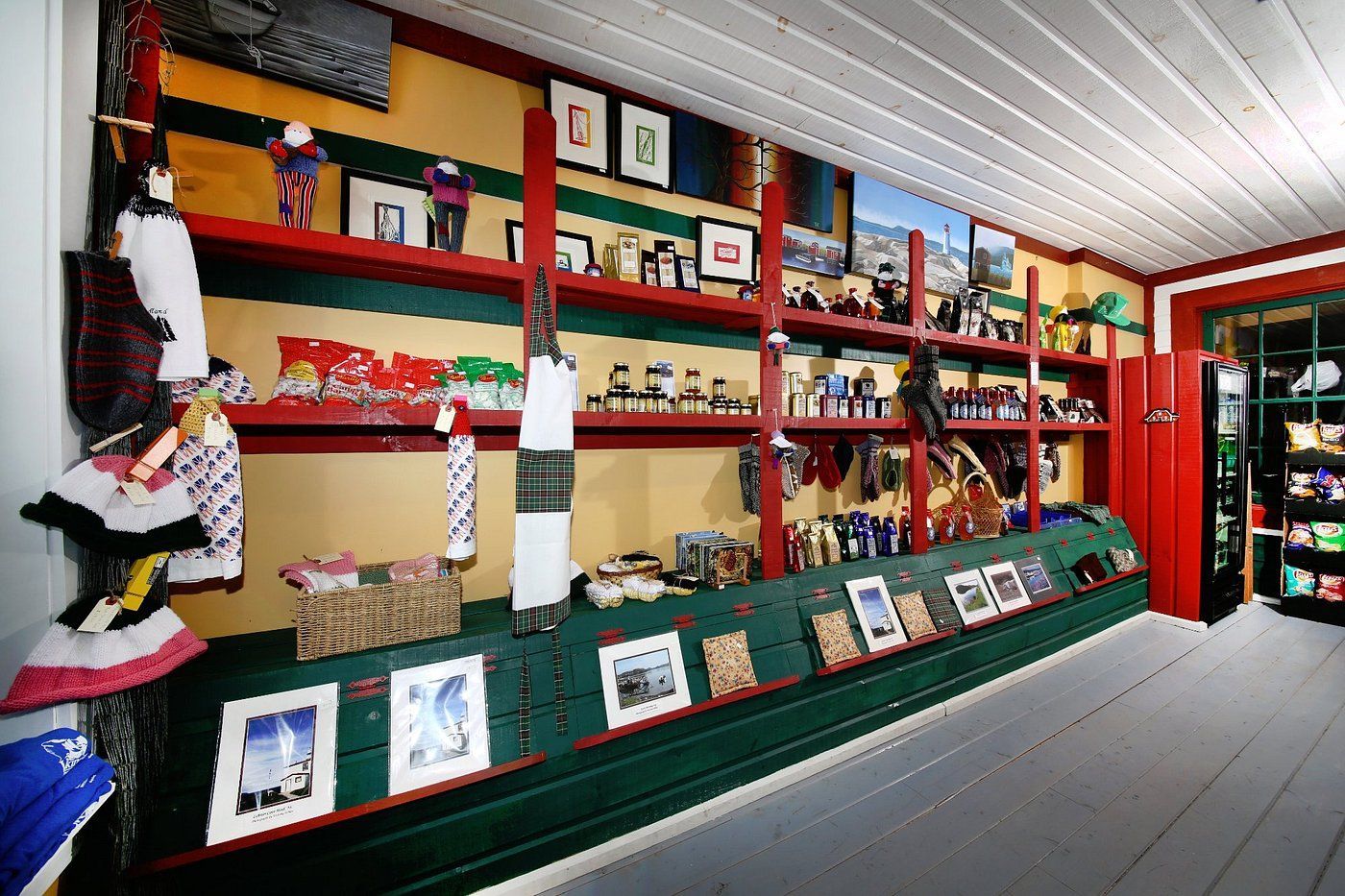 Interieur van een souvenirwinkel met rode schappen, handgemaakte spullen en een groene toonbank.